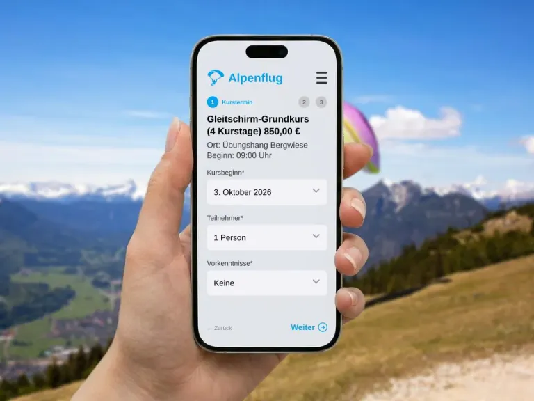 Smartphone with a booking form for a beginner paragliding course in front of a mountain landscape with a visible paraglider