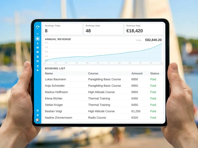 Tablet with an English Butlerapp dashboard for flight-school courses and payments in front of a blurred marina
