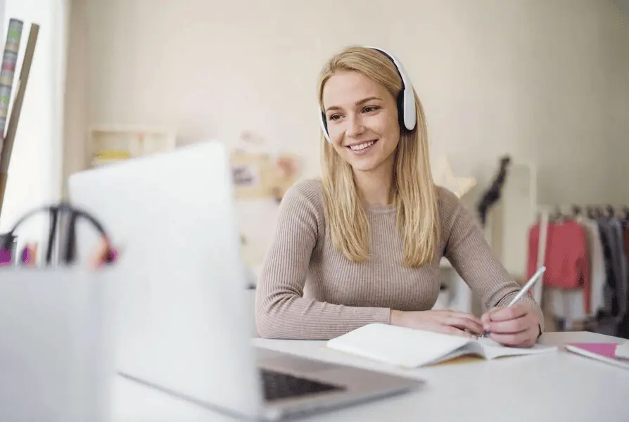 Zufriedene Sprachschüler sitzen im Unterricht und nutzen Laptops zur Kursbuchung